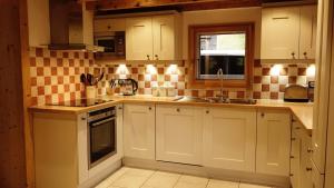 a kitchen with white cabinets and a sink at Chalet Mimi in Morzine +8 photos