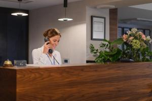 a woman in an office talking on a cell phone at Hotel Logos Kraków in Krakow