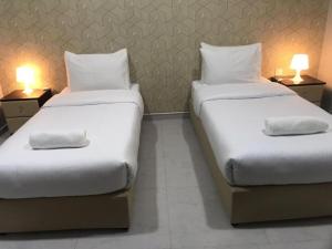 two twin beds in a room with two lamps at AL MARSA HOTEL APARTMENTS in Khor Fakkan