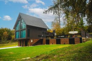 una casa con un tetto nero su un prato verde di Casa Negra a Brestovac