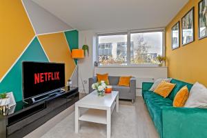 a living room with a green couch and a tv at Luxurious MK City Apartment- Walk to Train Station, Smart TV with Netflix, Disney Plus & Prime! in Milton Keynes