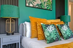 a bed with orange pillows and a green wall at Luxurious MK City Apartment- Walk to Train Station, Smart TV with Netflix, Disney Plus & Prime! in Milton Keynes
