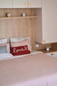 a bed with a red pillow with the word love on it at Little Nook in Čačak