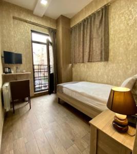 a bedroom with a bed and a desk and a window at Nizami Street Hotel in Baku
