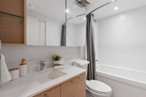 a white bathroom with a toilet and a sink at Elegant 2-Bedroom Duplex Haven in Vibrant Yaletown in Vancouver