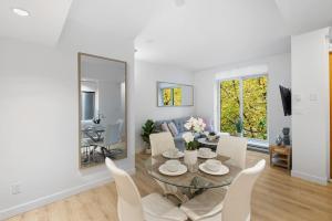 a dining room with a glass table and white chairs at Elegant 2-Bedroom Duplex Haven in Vibrant Yaletown in Vancouver