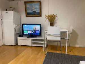 a television sitting on a white table with two chairs at Nice Apartment with1 bedroom Separate living room with a sofa bed and a tiny kitchen a bathroom located in Nordstrand near by the Sea for 3 guests with a garden and grill 5 extra guests with extra cost in the cabin with sea view just outside the apartment in Oslo