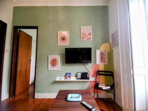 a living room with a television on a green wall at Tradicional Portuguese Apartment in Lisbon