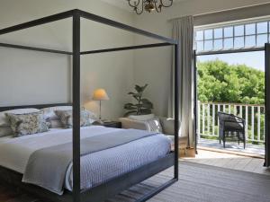 um quarto com uma cama de dossel e uma varanda em One Kensington Boutique Hotel em Cidade do Cabo
