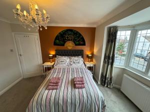 a bedroom with a large bed with a chandelier at 3 Bedroom House with Garden in London in Cheam