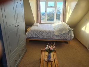 ein Schlafzimmer mit einem Bett und einer Vase aus Blumen auf einem Tisch in der Unterkunft Ensuite spare room in family home Dudley in Sedgley