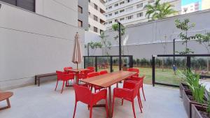 a patio with red chairs and tables and an umbrella at Nex One Ministro Ferreira Alves in Sao Paulo
