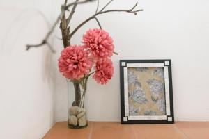 two pink flowers in a vase next to a picture at Hotel Boutique Al Alma in Santa Fe de Antioquia