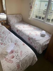 two twin beds in a room with a window at Cosy Cottage Caravan in Ashington