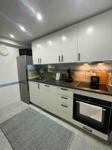 uma cozinha com armários brancos e um forno preto em Moderne ruhige Ferienwohnung em Ubstadt-Weiher