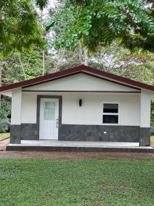 Casa pequeña con puerta blanca y porche en Roaring River Golf & Accommodations en Belmopan