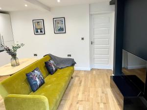 a living room with a yellow couch and a table at Palmer Apartment, 3 guests, Free Wifi, Great Transport Links, close to Uni, Hospital & Town Centre in Reading