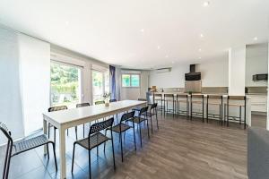 een open keuken en eetkamer met een lange tafel en stoelen bij Maison Frappaz 4 chambres avec jardin Villeurbanne in Villeurbanne