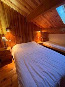 a bedroom with a white bed in a wooden room at Chalet Duplex vue sur le lac et pied des pistes in Les Angles