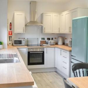 a kitchen with white cabinets and a stove top oven at Avocet Cottage Amble in Amble