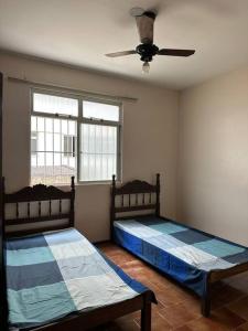 two beds in a room with a ceiling fan at APARTAMENTO TOP, Conforto e Qualidade in Guarapari