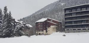 a building with snow on it in front of a mountain at Appartement cosy au pied des pistes in Corrençon-en-Vercors