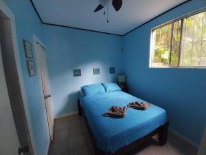 a blue bedroom with a bed with towels on it at Roatan Backpackers' Hostel in Sandy Bay