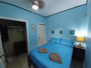 a blue bedroom with a bed with two towels on it at Roatan Backpackers' Hostel in Sandy Bay