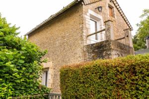 un antiguo edificio de ladrillo con una ventana y arbustos en Maisonnette duplex avec jacuzzi/sauna attenant en Saint-Martin-des-Entrées