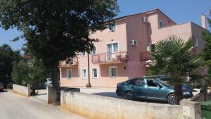 a blue car parked in front of a pink building at Apartment Studio Baric in Poreč