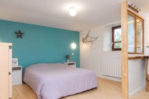1 dormitorio con cama blanca y pared azul en Maisonnette duplex avec jacuzzi/sauna attenant, en Saint-Martin-des-Entrées