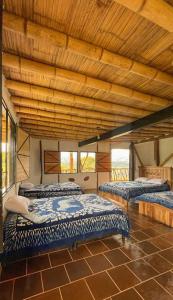 3 camas en una habitación con techo de madera en Hotel Rancho Maju, en San Agustín