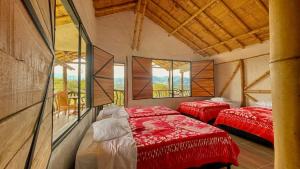 two red beds in a room with windows at Hotel Rancho Maju in San Agustín