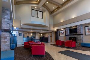 Best Western Plus South Edmonton Inn & Suites في إيدمونتون: لوبي وكراسي حمراء وموقد