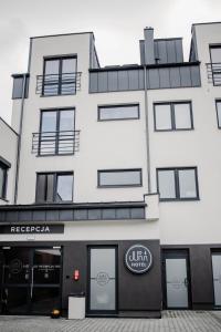 a white building with a sign in front of it at Jura Hotel Osiek in Olkusz