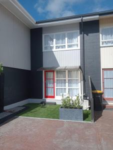 een huis met een rode deur en een groene tuin bij City Central in Nelson