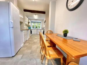 a kitchen and dining room with a wooden table and a clock at EasyRest - Spacious Detached House - 10 Beds - 5 Bedrooms - 4 Bathrooms - Secure Parking 5 Vehicles - Excellent Road Links - Perfect for Contractors & Large Groups in Grantham