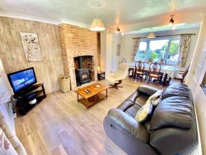 a living room with a leather couch and a fireplace at EasyRest - Spacious Detached House - 10 Beds - 5 Bedrooms - 4 Bathrooms - Secure Parking 5 Vehicles - Excellent Road Links - Perfect for Contractors & Large Groups in Grantham
