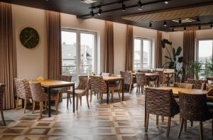 uma sala de jantar com mesas, cadeiras e janelas em Jura Hotel Osiek em Olkusz