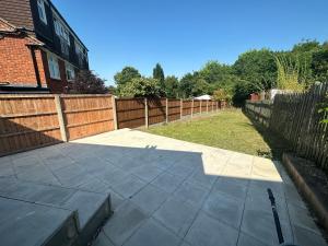 un patio trasero con una valla y un patio de hormigón en 5 bedroom house in Orpington en Orpington