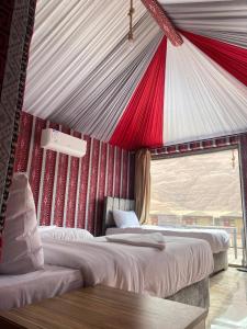 two beds in a room with a red and white ceiling at V D C Wadi Rum in Disah
