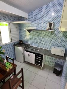 cocina con fregadero y paredes de azulejos azules en Kitnets em Caraguatatuba en Caraguatatuba