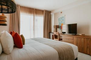 a bedroom with a bed and a desk and a television at Selina Tulum Downtown in Tulum