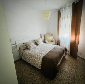 1 dormitorio con 1 cama y 1 silla en Apartamento Almazara, en Valencia de Alcántara