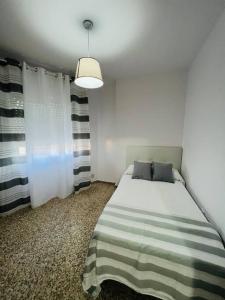 1 dormitorio con 1 cama con manta a rayas en Apartamento Almazara, en Valencia de Alcántara