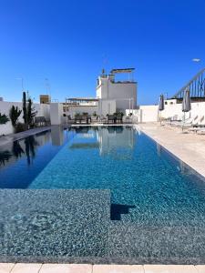 een groot zwembad met blauw water voor een gebouw bij Zahra Superior Suite with private pool in Sannicola