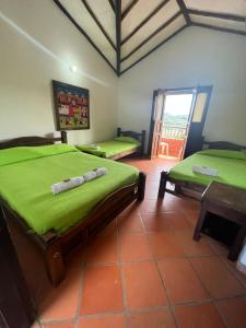 una camera con due letti con lenzuola verdi e un tavolo di Elizabeth Country House a Curití