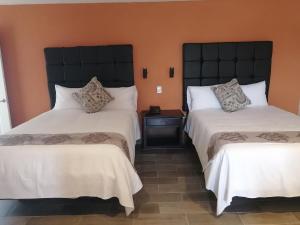 Duas camas num quarto com paredes cor de laranja em Hotel Express Inn em Sabinas