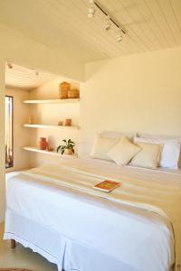 1 cama blanca grande en una habitación con estanterías en Evoé Caraíva, en Caraíva