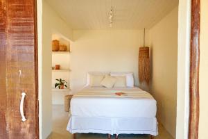 een slaapkamer met een wit bed in een kamer bij Evoé Caraíva in Caraíva